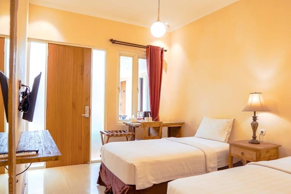 Una habitación de hotel con dos camas, un escritorio, una silla, una lámpara y un armario.
