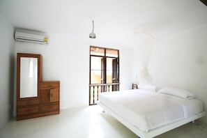 Camera da letto con un letto, una cassettiera in legno, uno specchio, un condizionatore d'aria, una finestra con vista e un lampadario.