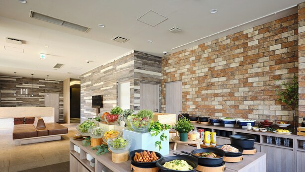 A modern kitchen area with a buffet setup, including various food items and cooking appliances. - Hotel MONday Haneda Airport (Tokyo)