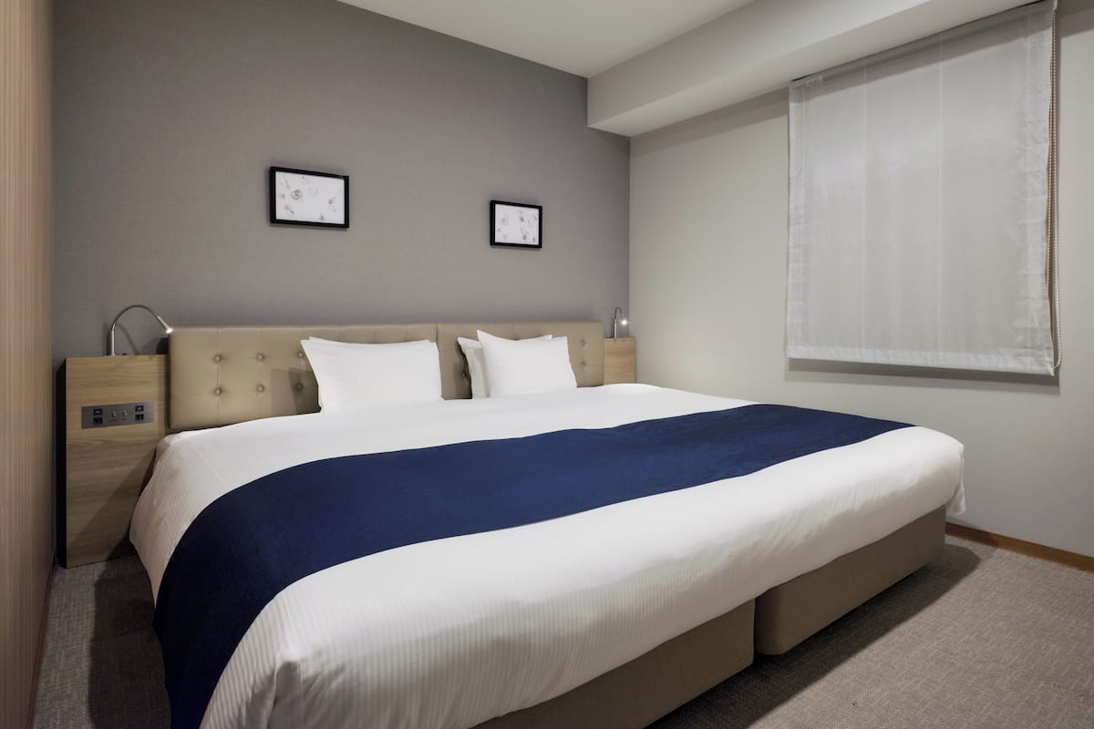A modern bedroom with a large bed, bedside tables, and two framed pictures on the wall.