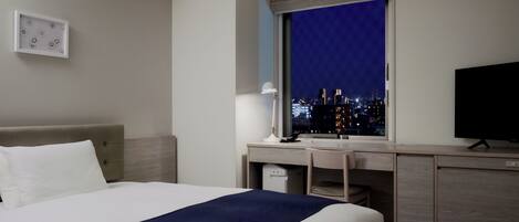 A hotel room with a bed, desk, and TV.