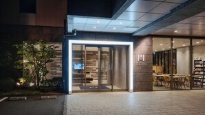 A modern building entrance with glass doors, a brick facade, and a sign reading "MONDAY". - Hotel MONday Haneda Airport (Tokyo)