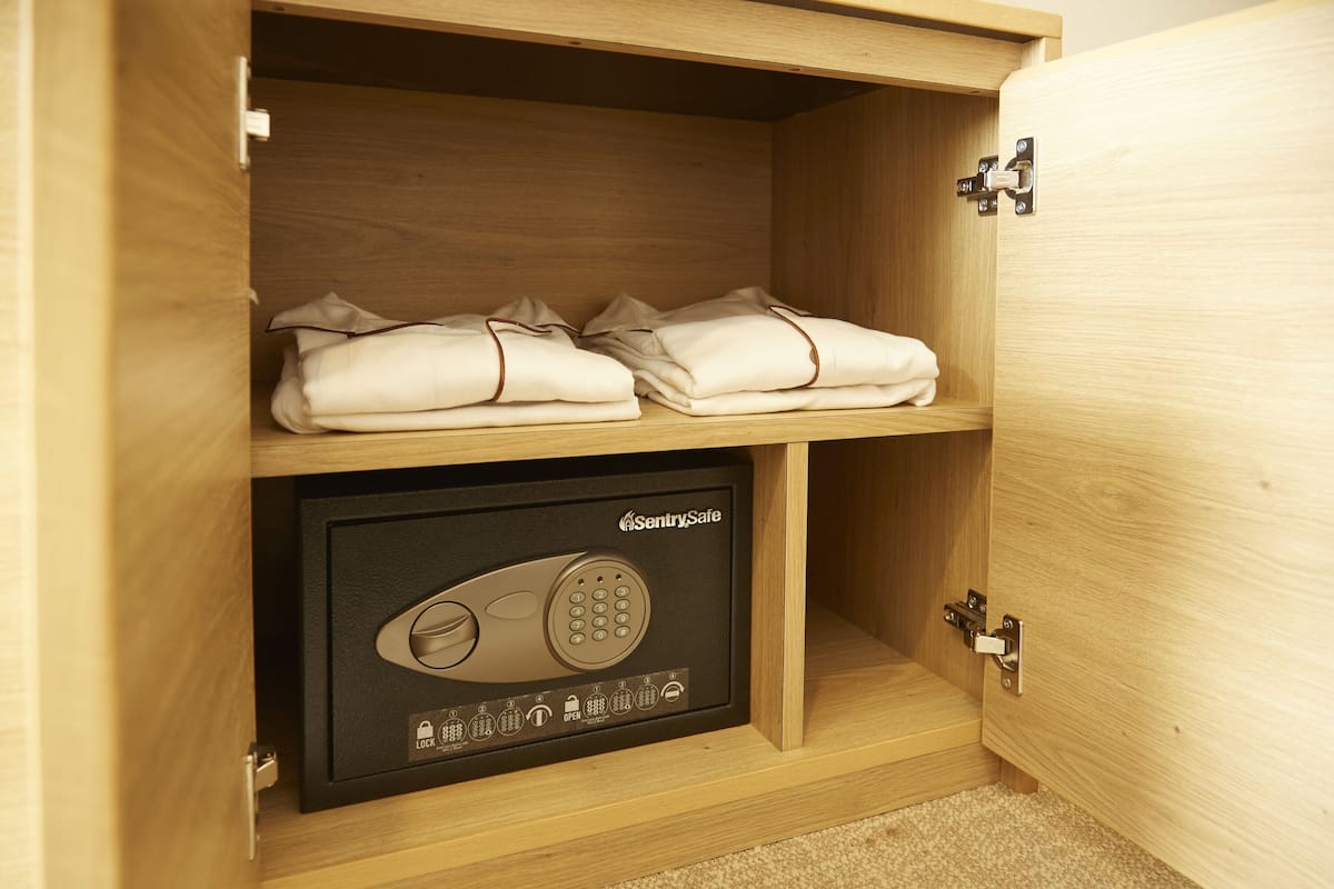 A wooden cabinet with a safe containing a keypad lock.