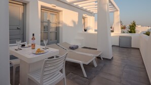 A rooftop terrace with a table set for dining, lounge chairs, and a view of the cityscape.