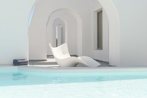 Una piscina al aire libre, sillones reclinables de piscina