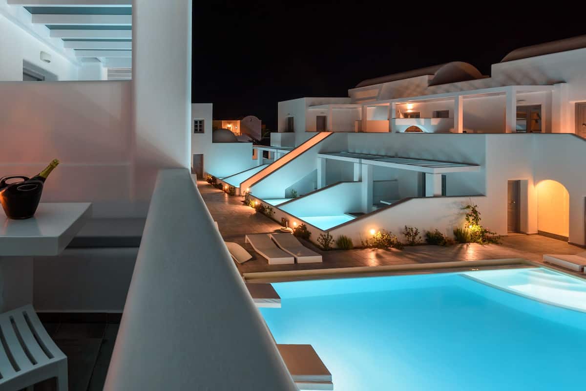 Uma área moderna com piscina ao ar livre e espaço de refeições, incluindo mesa com copos e garrafa, e uma cadeira branca.