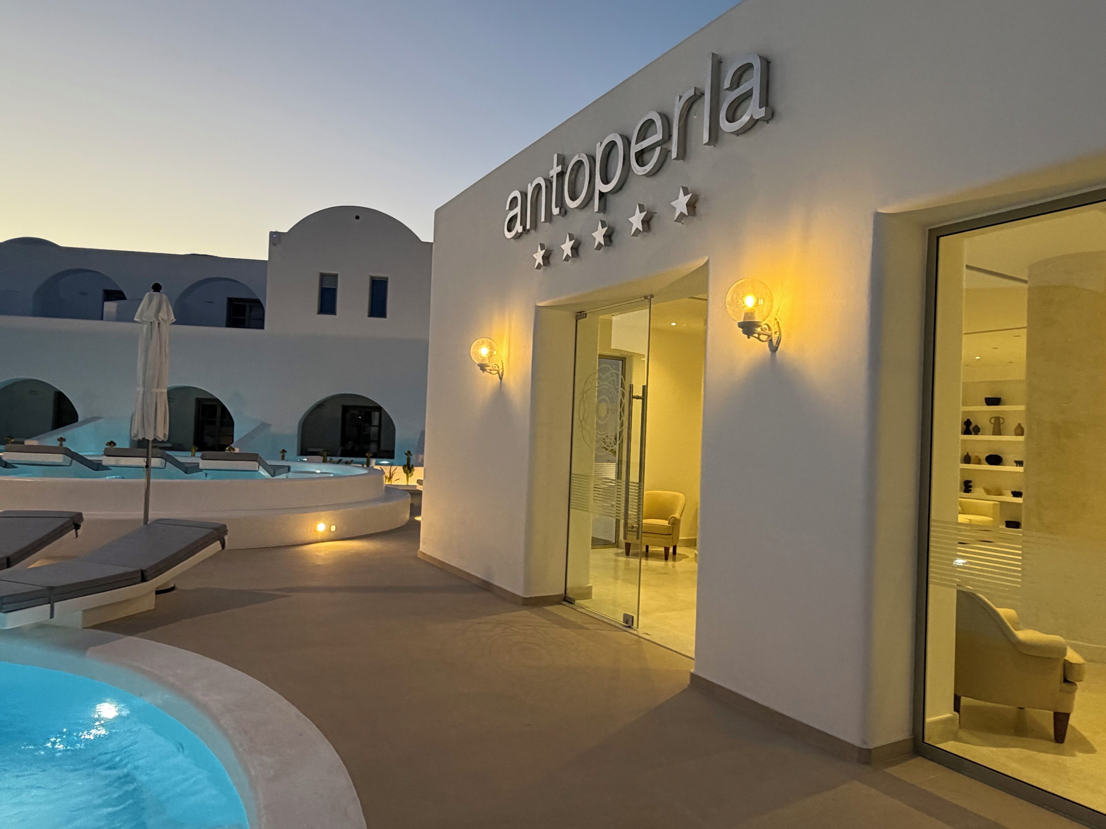 A modern building with a pool, lounge chairs, and a glass entrance.