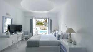 A modern bedroom with a bed, TV, and a view of a pool.