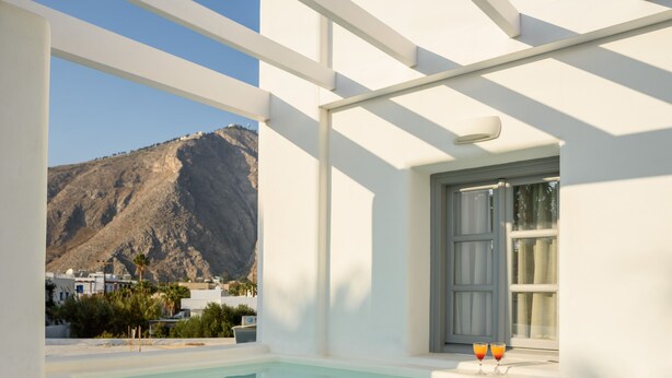 A modern indoor pool area with a view of a mountain and buildings in the background.