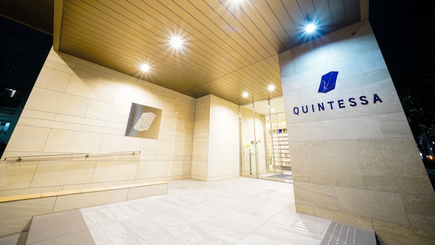 A modern building entrance with a wooden ceiling, a glass door, and the name 'QUINTESSA' on a pillar. - Quintessa Hotel Tokyo Haneda Comic & Books (Tokyo)
