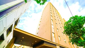 A hotel entrance with a modern architectural design, featuring a prominent entrance canopy and a visible name sign. - Quintessa Hotel Tokyo Haneda Comic & Books (Tokyo)
