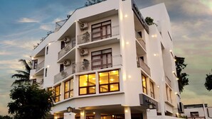 Un hôtel à plusieurs étages doté de balcons, de climatiseurs et d’une façade bien éclairée.