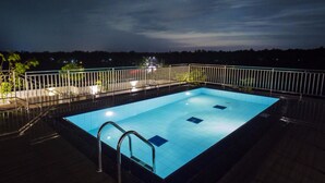 Une piscine rectangulaire dotée d’une rambarde métallique, entourée d’une terrasse en bois.