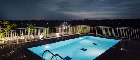 Una piscina rectangular con barandilla de metal, rodeada por una cubierta de madera.