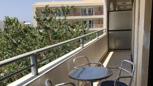 Un balcó amb taula i dues cadires, una barana i un edifici al fons.