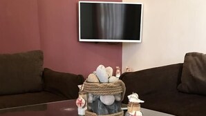 Un saló amb una taula de café de vidre, una televisió penjada a la paret i una decoració de pedra sobre la taula.