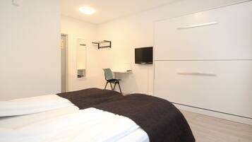 Une chambre à coucher avec un lit, une chaise, un téléviseur et une armoire.