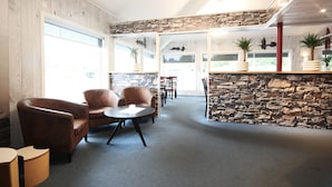 A modern interior with stone walls, leather sofas, and a dining area. - Napoli resturant & Hotell (Alstahaug)