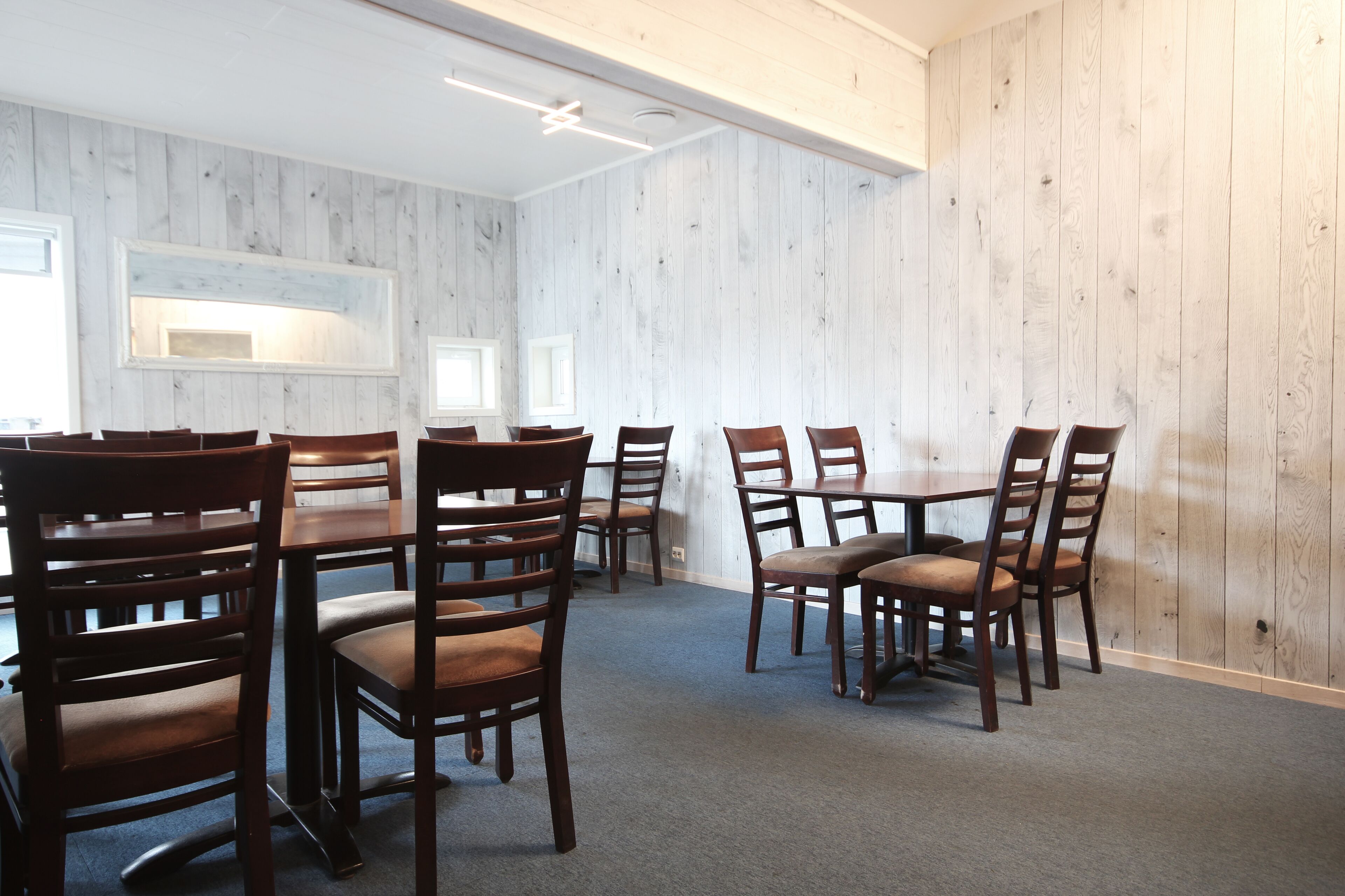 A dining area with wooden walls and multiple tables and chairs.