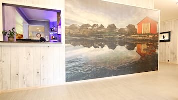 Welcome to our reception area, where a large painting of a serene lakeside scene sets the tone for a peaceful stay.