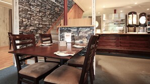 A dining area with a stone wall, wooden staircase, and a kitchen area with appliances. - Napoli resturant & Hotell (Alstahaug)