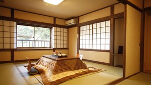 Um quarto japonês tradicional com piso de tatame, portas deslizantes e uma mesa baixa com almofadas.