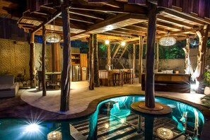 A pool area with a wooden deck, lounge chairs, and a bar area. - Gili Treehouses (Gili Trawangan)