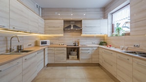 A modern kitchen with light wood cabinets, stainless steel appliances, and a window with a view. - Willa Wrzos (Zakopane)