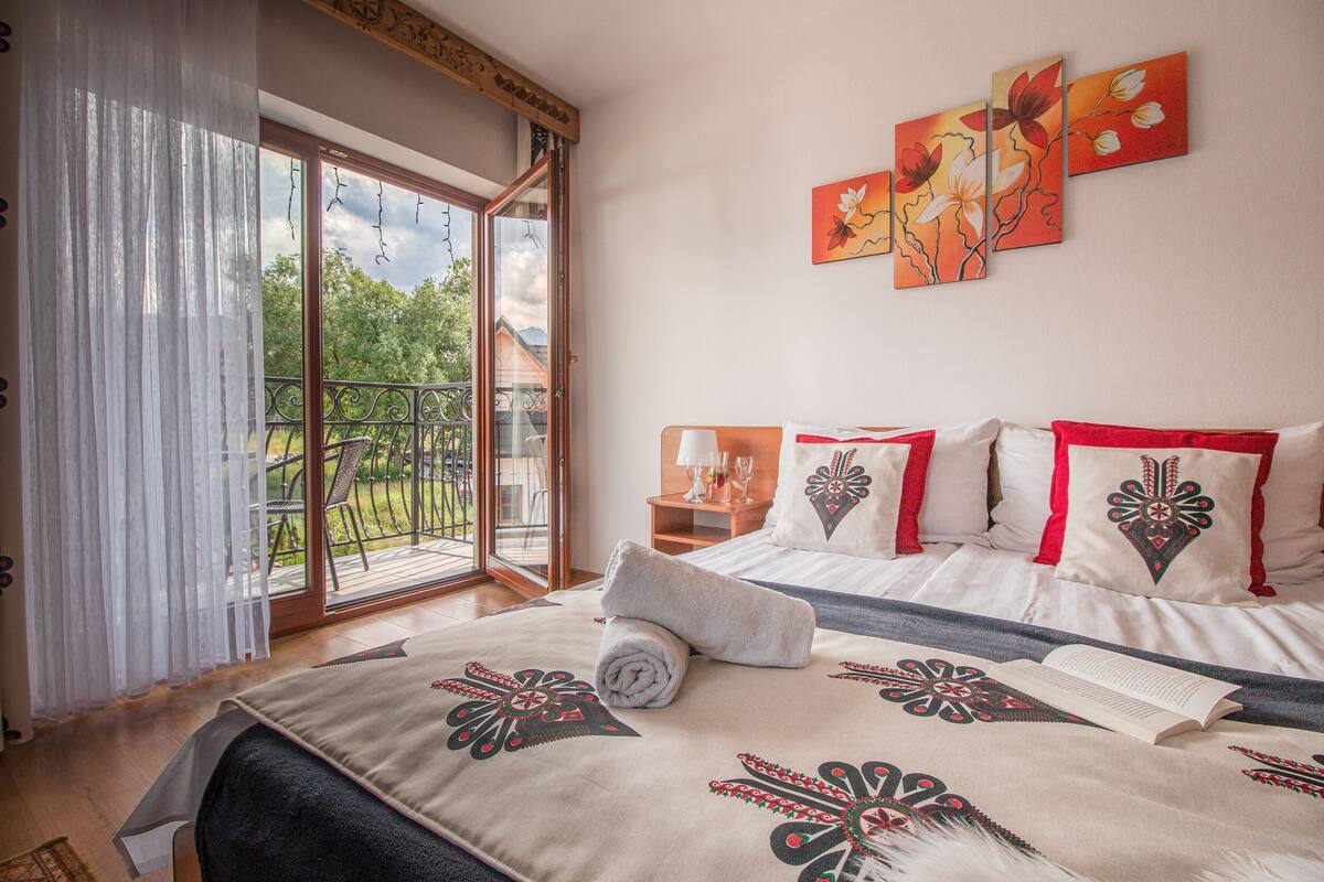 Un dormitorio con una cama grande, un balcón con vistas y un cuadro en la pared.