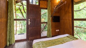 A wooden room with a bed, a door, and windows. - Eighth Wonder Resort (Sigiriya)