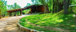 A covered outdoor area with a wooden deck, surrounded by trees and a well-maintained lawn. - Eighth Wonder Resort (Sigiriya)