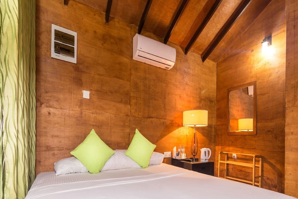 A wooden room with a bed, a nightstand, a lamp, and an air conditioning unit.