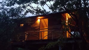 A wooden cabin with a balcony, surrounded by trees. - Eighth Wonder Resort (Sigiriya)