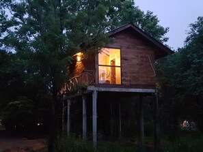 A wooden cabin with a balcony, surrounded by trees. - Eighth Wonder Resort (Sigiriya)