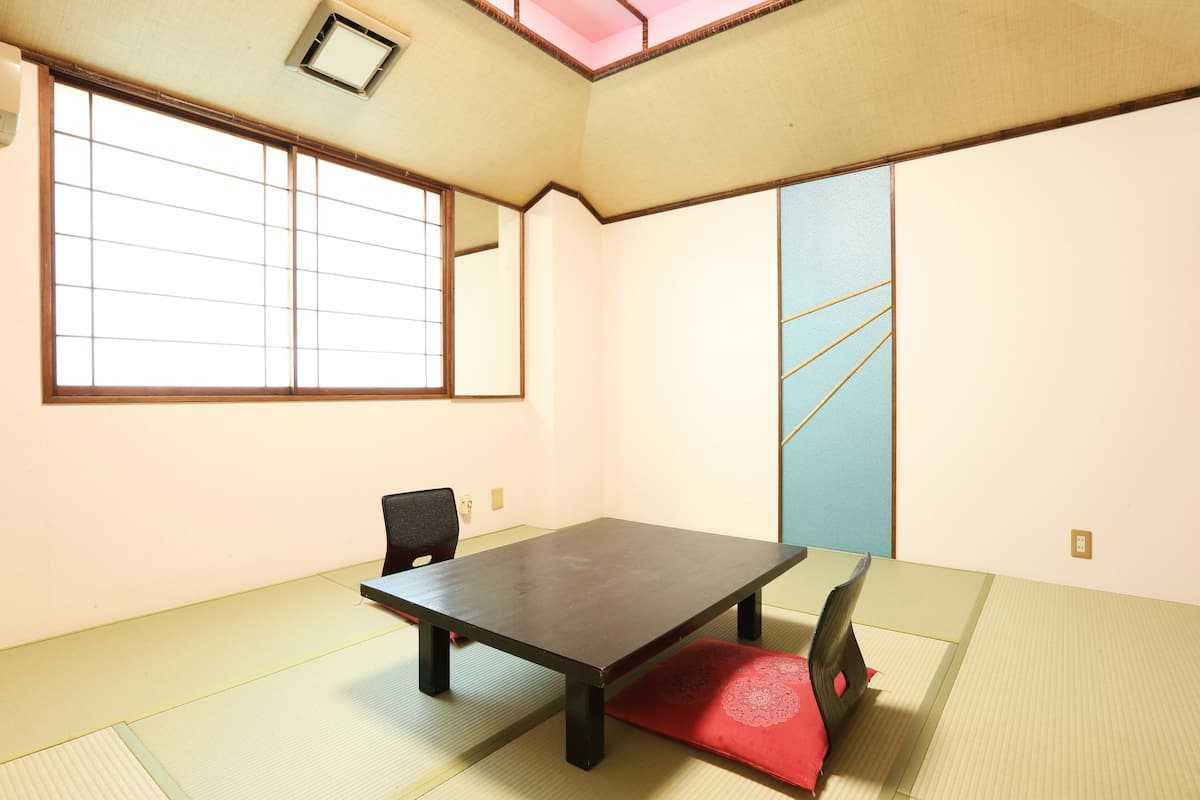 Een traditionele Japanse kamer met tatami matten, een lage tafel, een schuifdeur en een raam met een rasterpatroon.