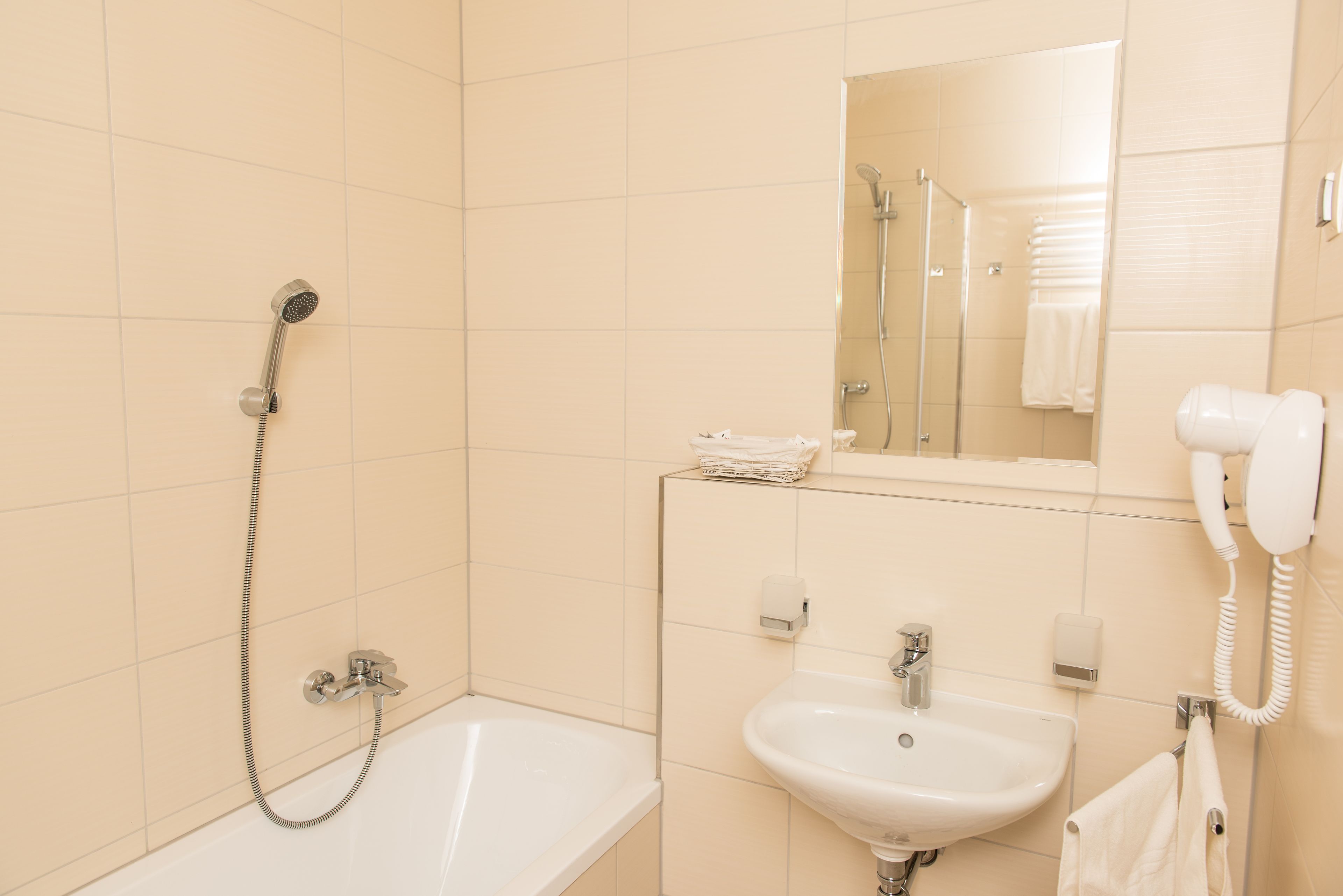 A bathroom with a bathtub, a sink, a mirror, and a shower.