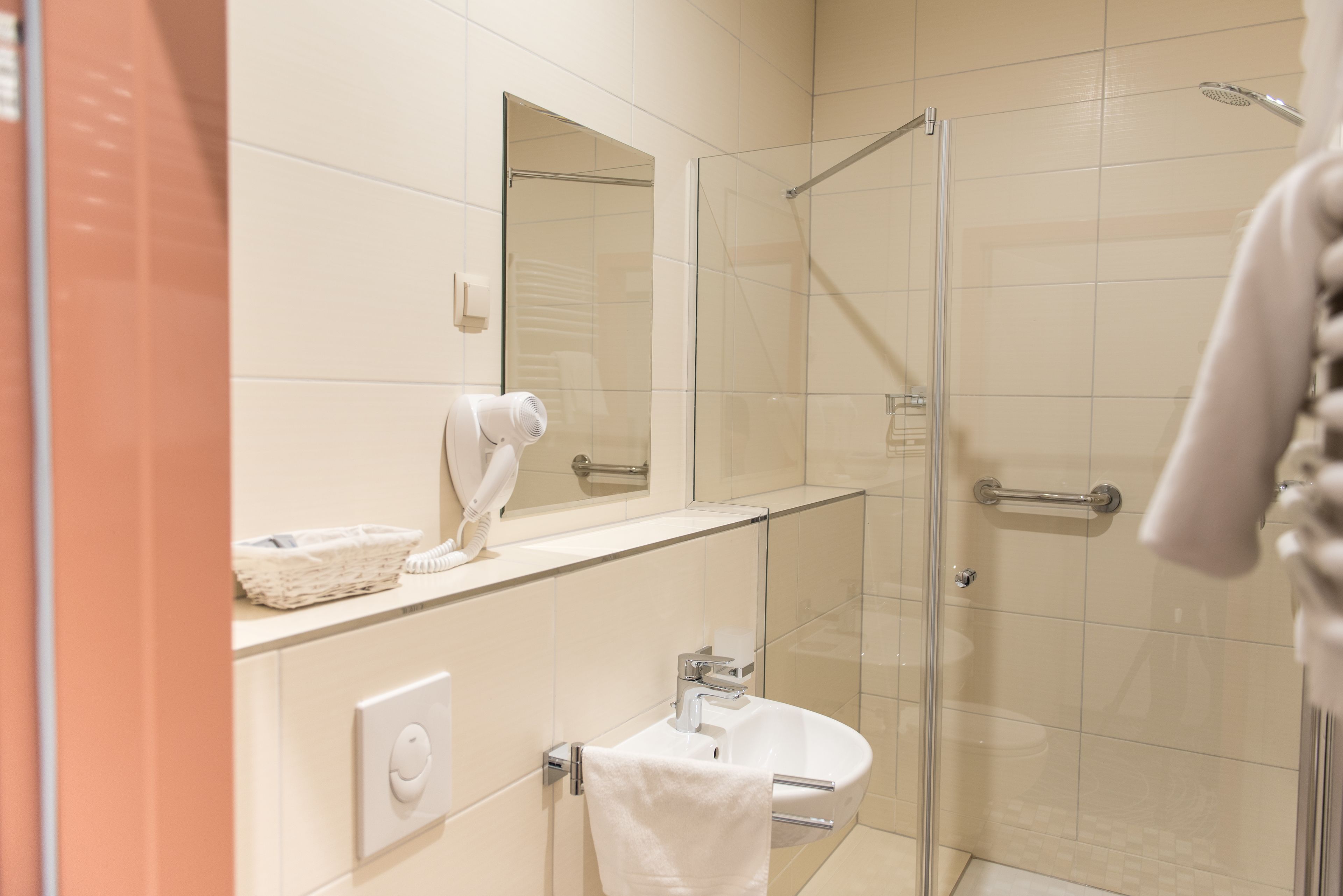 Un bagno moderno con box doccia in vetro, un lavabo e un porta asciugamani.