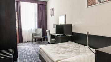 Une chambre d’hôtel comprenant un lit, un bureau, une chaise, un téléviseur et une armoire.