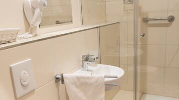 A bathroom with a toilet, sink, and shower area.