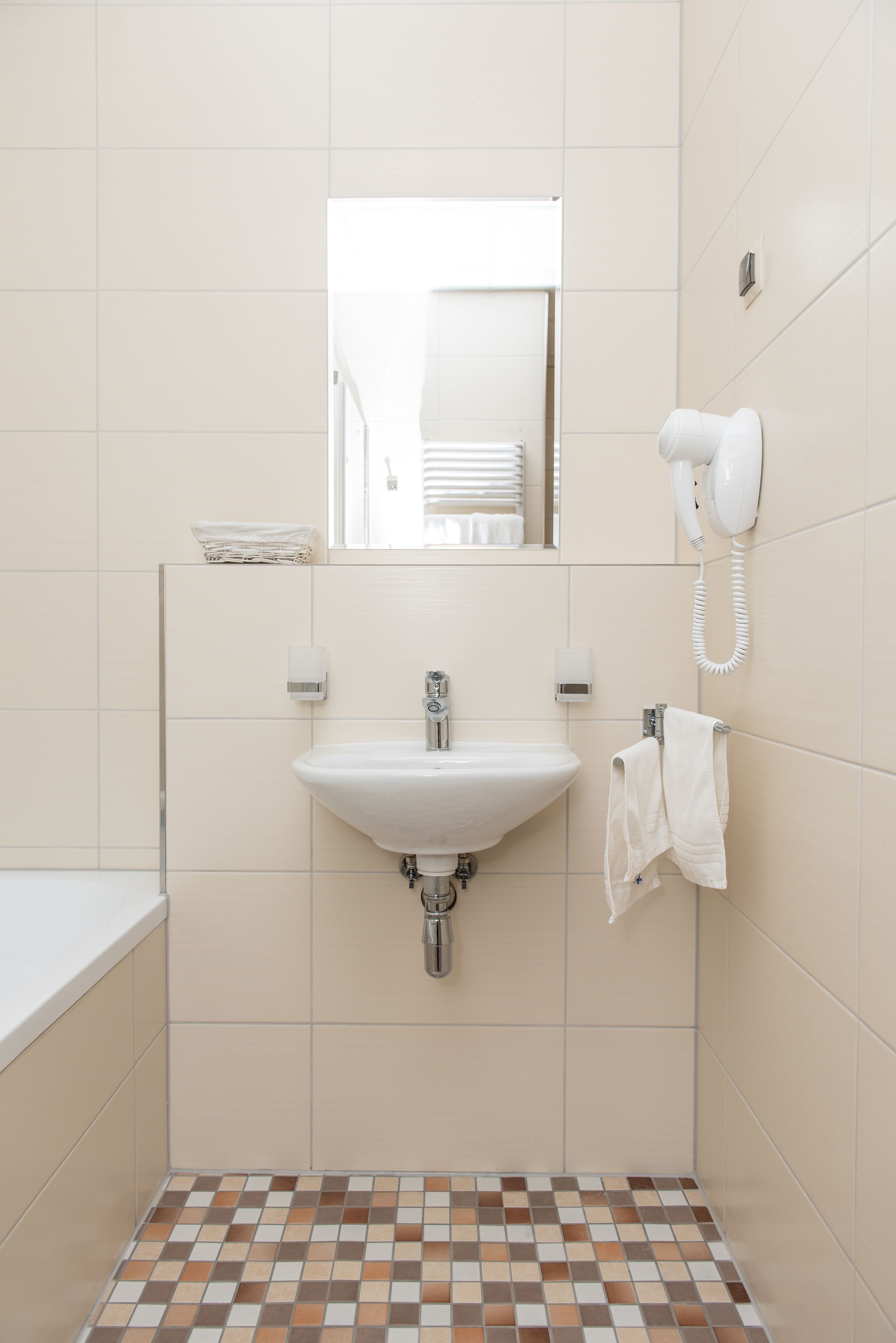 A bathroom with a sink, mirror, towel rack, and a hairdryer.