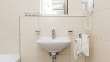 A bathroom with a sink, mirror, towel rack, and a hairdryer.