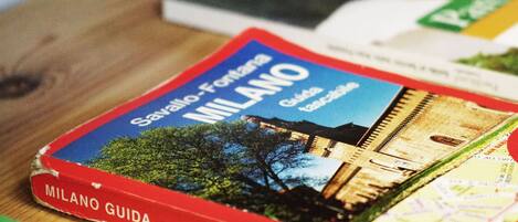 A guidebook titled 'Milano Guida' with a cover image of a building and trees.