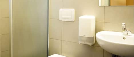 A bathroom with a toilet, a hand dryer, and a sink.