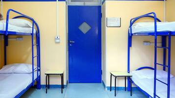 A room with bunk beds, a door, and a small table.