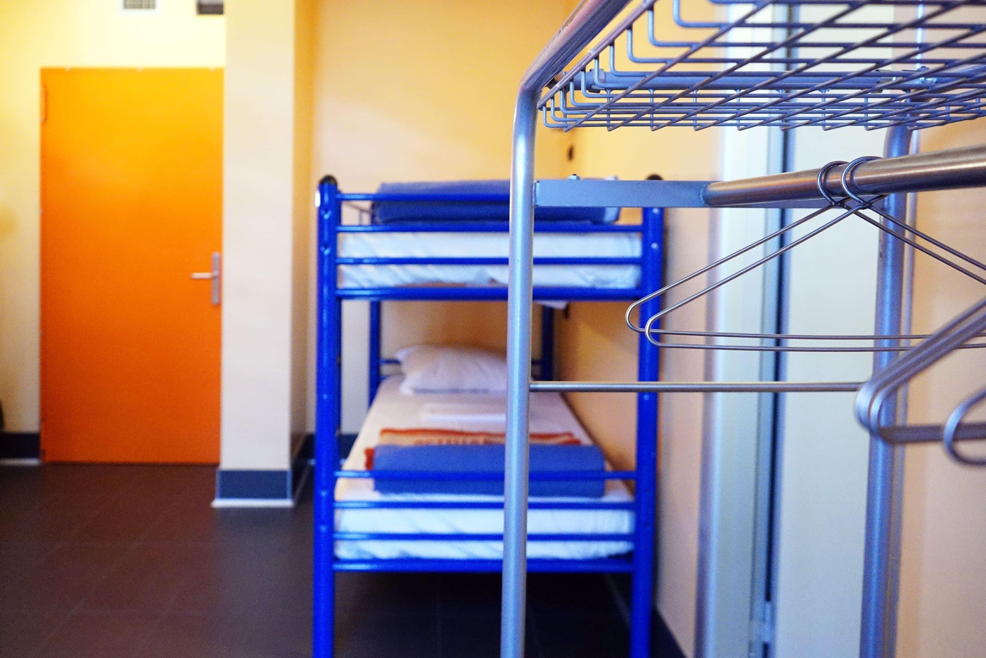 Een stapelbed met metalen spijlen, een deur en een betegelde vloer.