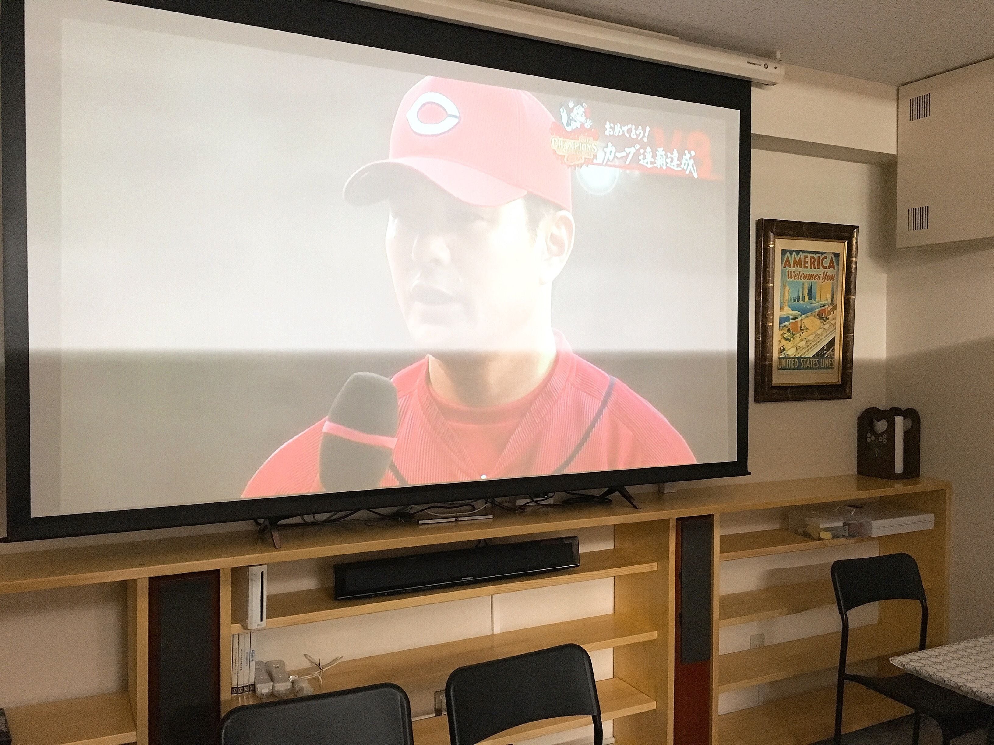 A television mounted on a wooden stand with a framed poster on the wall.