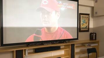 A television mounted on a wooden stand with a framed poster on the wall.