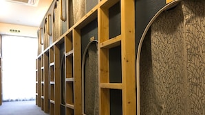 A hallway with wooden shelving units and a patterned wall. - Hostel Mallika (Hiroshima)