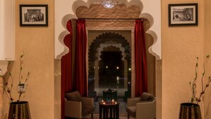 Una habitación con dos sillones, una pequeña mesa con velas y un arco decorativo.
