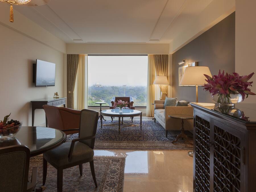 A hotel room with a dining area, a sofa, a TV, and a view of the outdoors.